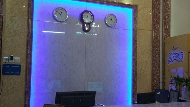 Uma receção com relógios, uma parede de mármore e uma iluminação azul.