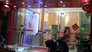 Entrada de hotel com portas de vidro, balcão de recepção e uma scooter estacionada na frente.