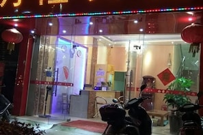 Entrada d'hotel amb portes de vidre, una recepció i una moto aparcada a l'exterior.