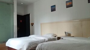 Quarto de hotel com duas camas, um painel de cabeceira de madeira e uma mesinha de cabeceira com abajur.
