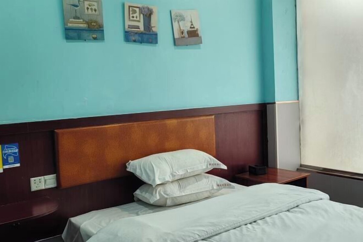 Una habitación de hotel con cama, almohadas, mesita de noche y decoración en la pared.