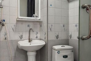 Un baño con lavamanos pedestal, inodoro y zona de ducha.