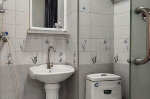 A bathroom with a pedestal sink, a toilet, and a shower area.