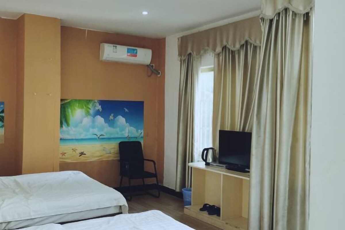 Habitación de hotel con dos camas, un cuadro de una escena de playa, un televisor sobre un soporte y un equipo de aire acondicionado.