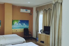 Habitación de hotel con dos camas, un cuadro de una escena de playa, un televisor sobre un soporte y un equipo de aire acondicionado.