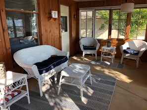A cozy room with wicker furniture, including a sofa and chairs, a small table, and a rug.