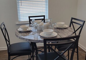 Enjoy meals in this dining area with a round table and six chairs, set with white tableware and glass bottles.