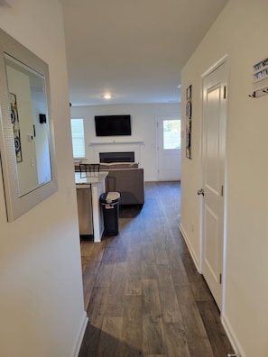 Cozy living space with a flat-screen TV above the fireplace, dining area, and wooden flooring.