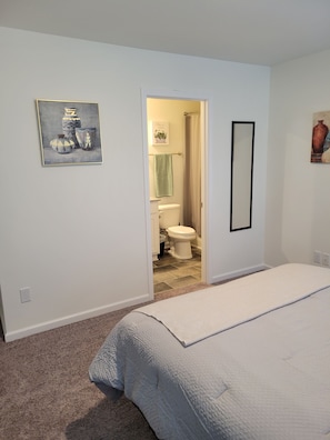 Relax in a serene space with a large bed, wall-mounted mirror, and framed artwork.