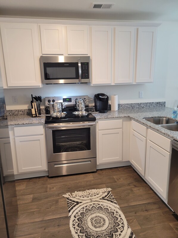 Enjoy cooking in this well-equipped kitchen with a microwave, stove, and oven, along with a coffee maker and dish soap.