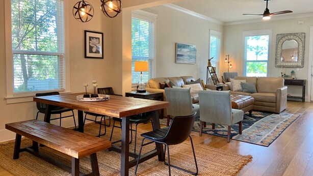 A spacious living room with a wooden dining table, comfortable seating, and large windows. - Perfect beach getaway! Bike to beach, pool - 4 cruisers included! (Rosemary Beach)