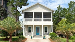 A two-story house with a front porch, a blue door, and a brick pathway leading to the entrance. - Perfect beach getaway! Bike to beach, pool - 4 cruisers included! (Rosemary Beach)