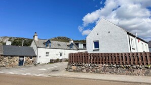 A white building with a stone wall and wooden fence in front. - Cute, comfy bolthole in an amazing spot to explore from. (Kinlochbervie, near Lochinver)
