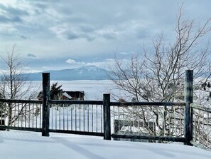 A snow-covered landscape with a wooden fence in the foreground and a mountain in the background.