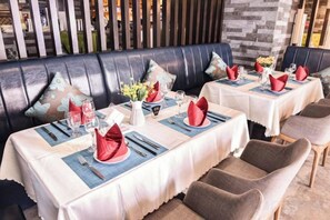 Un restaurante con mesas dispuestas para comer, que cuenta con un área de cabinas y una barra.