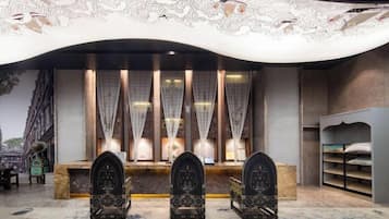 A room with a reception desk, two ornate chairs, a patterned carpet, and a decorative ceiling.