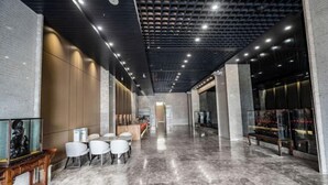 A modern lobby with a marble floor, seating area with white chairs, a reception desk, and a glass display case. - Wen Chang Tiancheng Hotel (Wenchang High-speed Railway Station Wennan Old Street Branch) (Wenchang)