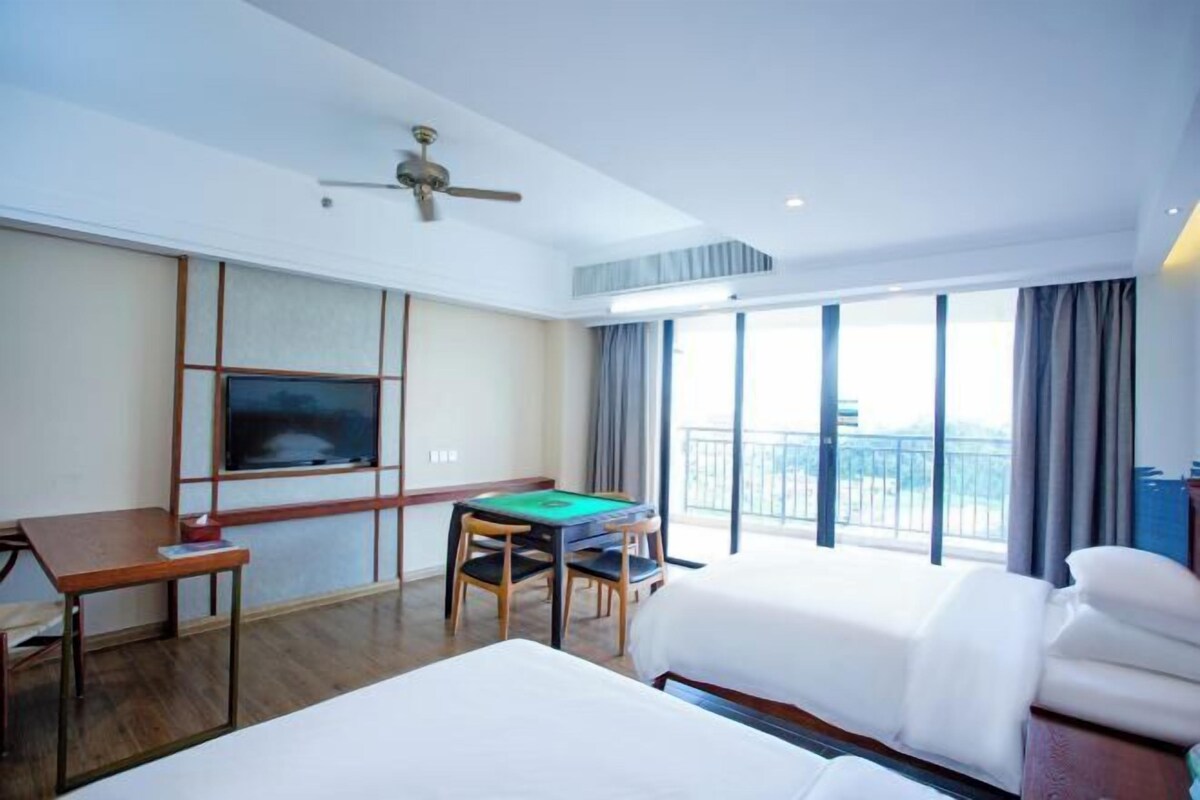 Une chambre d’hôtel avec deux lits, un bureau, une table de billard, une télévision et un balcon avec vue.