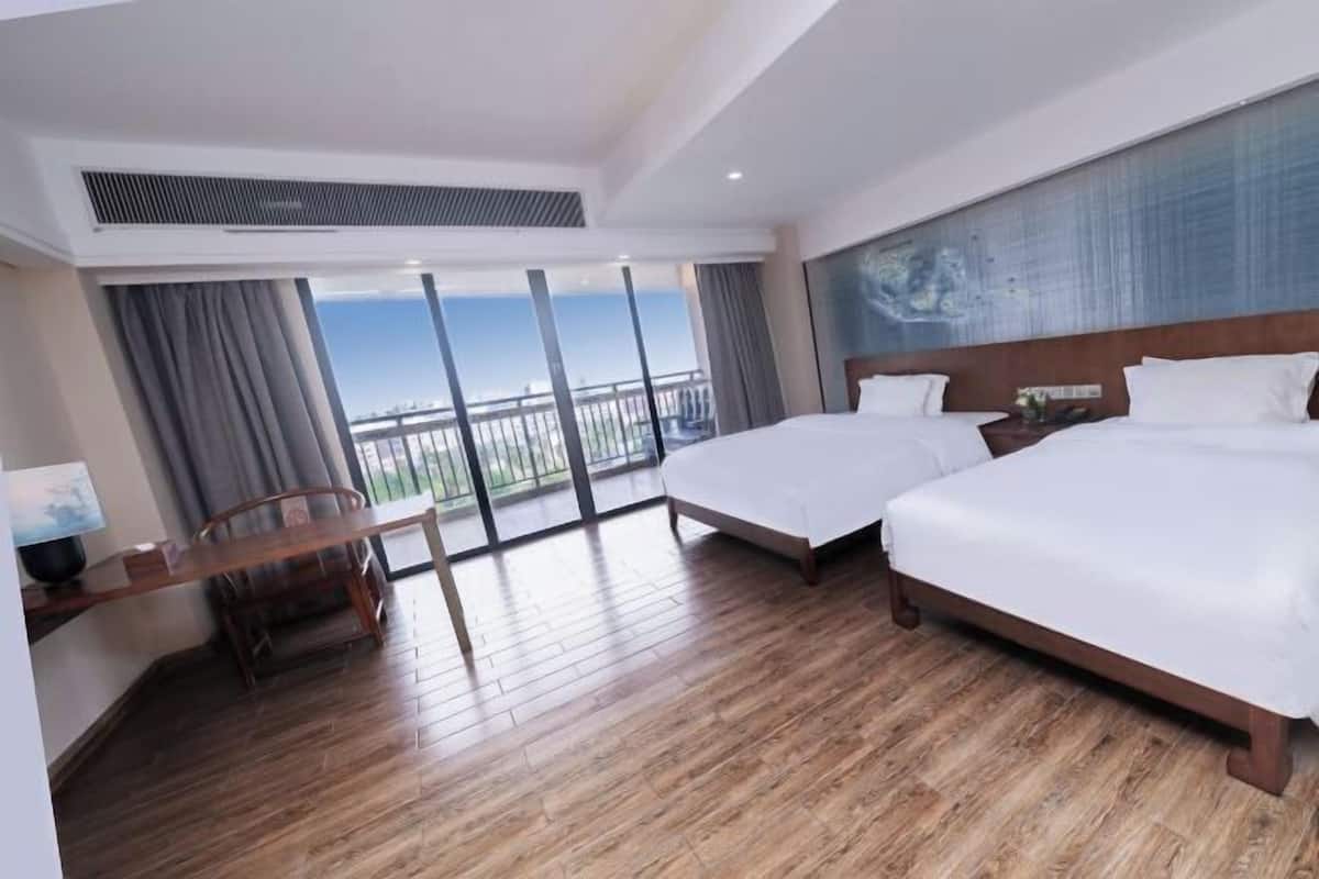 Une chambre d’hôtel avec deux lits, un bureau et une chaise.