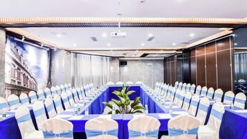 A conference room with a long table, chairs with blue sashes, and a plant centerpiece.