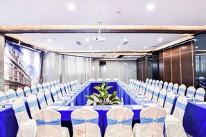 A conference room with a long table, chairs with blue sashes, and a plant centerpiece. - Wen Chang Tiancheng Hotel (Wenchang High-speed Railway Station Wennan Old Street Branch) (Wenchang)
