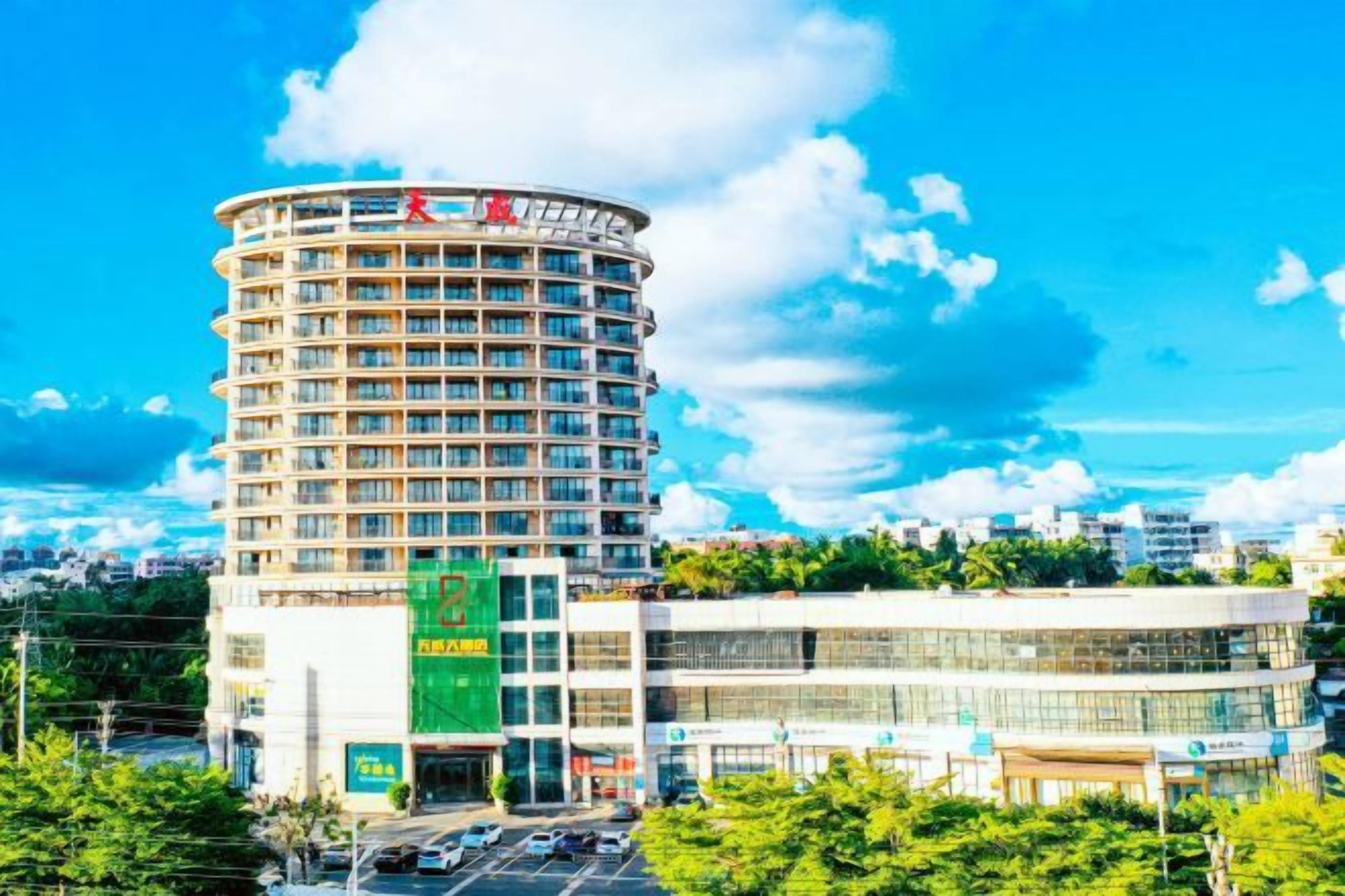 A multi-story hotel with a curved facade, a large glass entrance, and a parking lot in front.