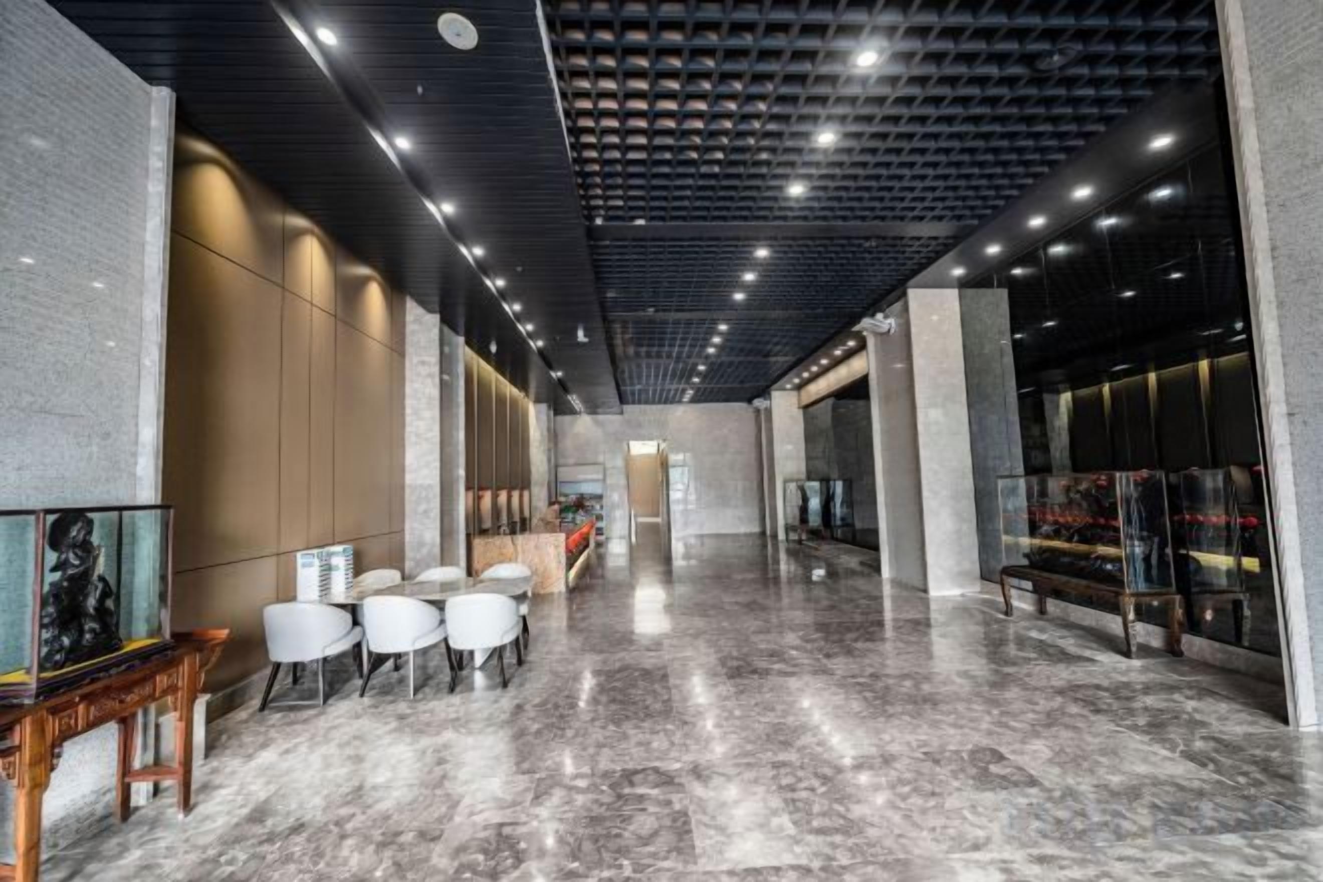 Un vestíbul modern amb sòl de marbre, zona de seients i taulell de recepció.
