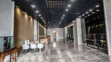 Un vestíbul modern amb sòl de marbre, zona de seients i taulell de recepció.