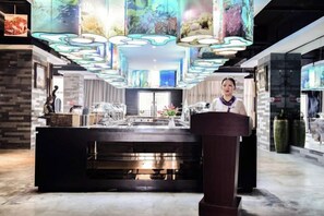 Een modern interieur met een bar in het midden, decoratieve plafondlampen en een grote vaas.