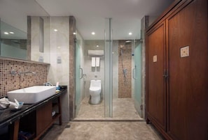A modern bathroom with a large sink, a glass-enclosed shower, and a wooden wardrobe.