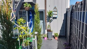 En smal gränd i staden med krukväxter, en blå flagga och ett staket av metall.