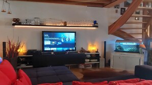 Ett vardagsrum med en tv, ett akvarium och en trappa.