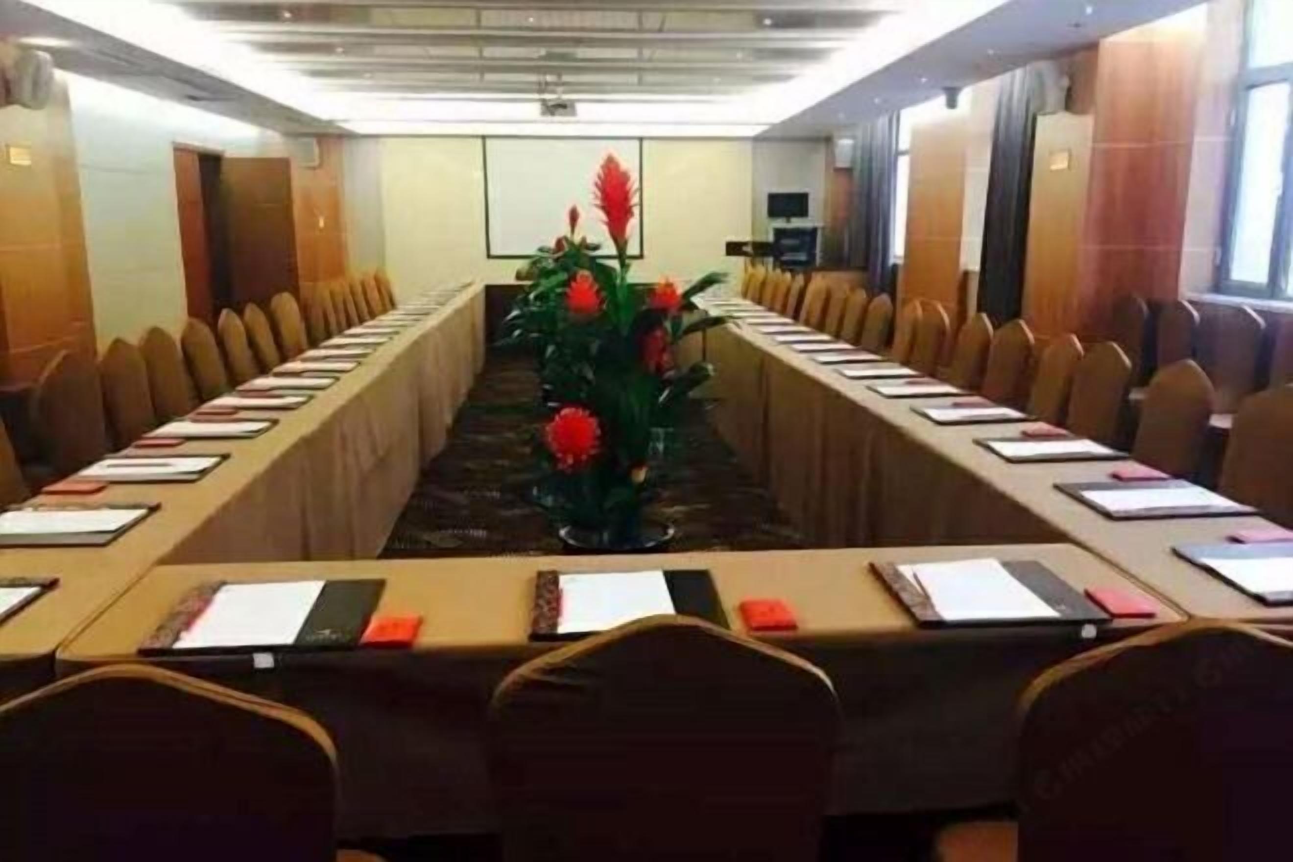 Une salle de conférence avec une longue table, des chaises et une plante décorative.