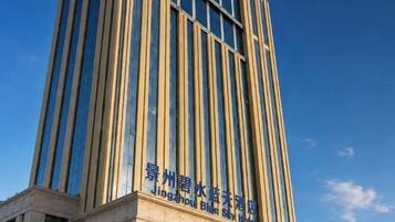 A tall building with vertical lines and a sign indicating it is the Jingzhou Blue Star Hotel.