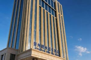 Un edificio alto con líneas verticales y un letrero que indica que es el Hotel Jingzhou Blue Star.