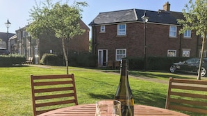 A wooden table with a bottle of wine, a glass, a bowl of chips, and a book titled "Three Act Tragedy". - I just love the location of Arthur’s Place within ’The Bay’. (Filey)