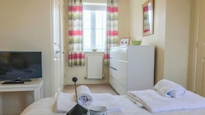A hotel room with a bed, a television, a dresser, and a window with curtains. - I just love the location of Arthur’s Place within ’The Bay’. (Filey)
