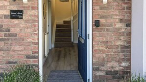 A brick exterior with a blue door, a sign reading "Arthur's Place 102 Sunrise Drive," and a wooden staircase leading inside. - I just love the location of Arthur’s Place within ’The Bay’. (Filey)