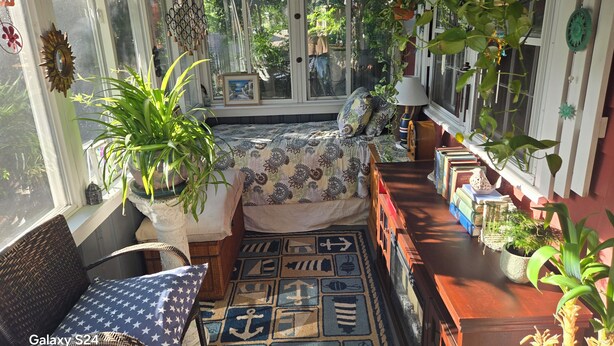 A cozy room with a bed, a chair, a table, and various plants. - Cozy Lakeside Cottage Just Steps To The Beach (Mashpee)
