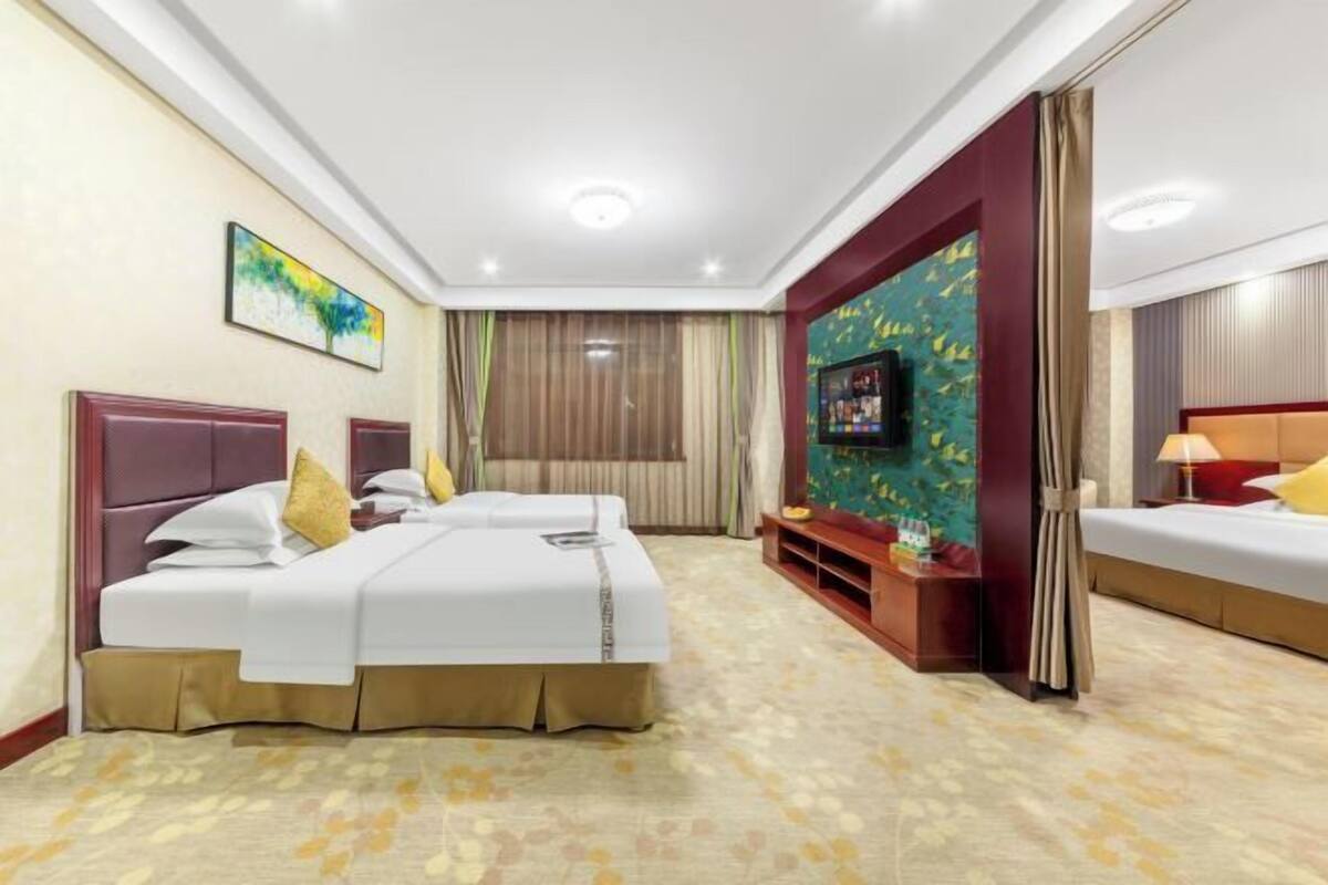 Une chambre d’hôtel avec deux lits, une télévision et un petit coin salon.