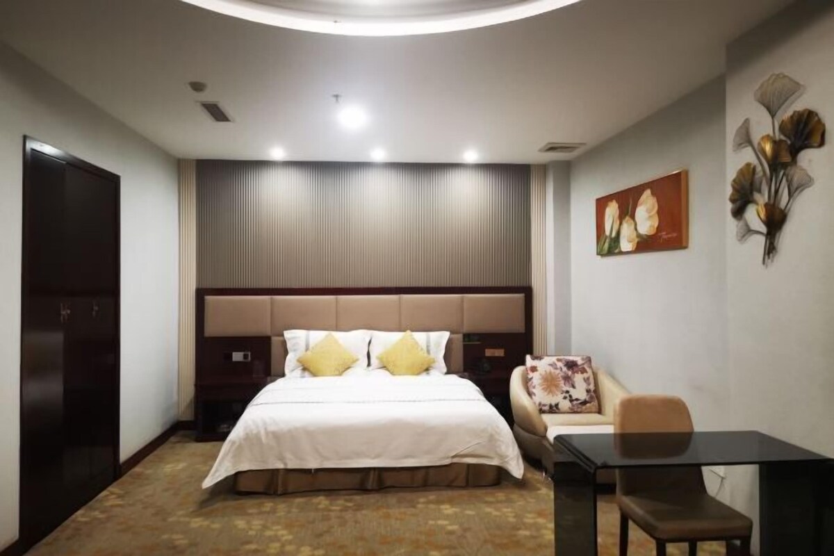 Une chambre d’hôtel avec un lit, un bureau, une chaise, une télévision et un tableau au mur.