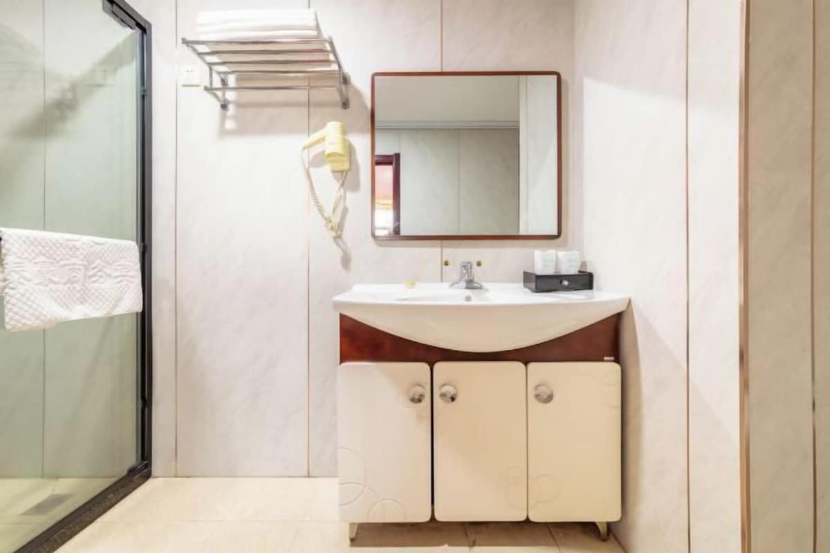 Une salle de bain moderne avec une douche à l’italienne en verre, un lavabo blanc avec un meuble-vasque en bois et un miroir au-dessus du lavabo.