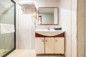 Une salle de bain moderne avec une douche à l’italienne en verre, un lavabo blanc avec un meuble-vasque en bois et un miroir au-dessus du lavabo.