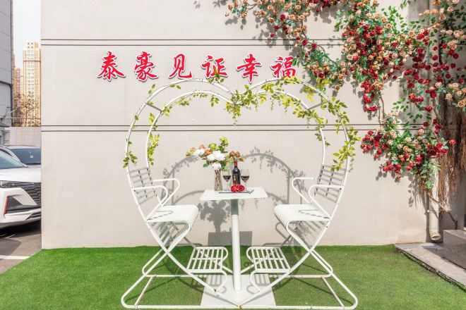 A heart-shaped outdoor seating area with a table and chairs, surrounded by greenery and flowers.