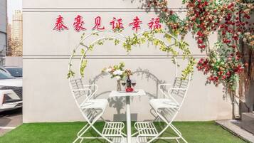 A heart-shaped outdoor seating area with a table and chairs, surrounded by greenery and flowers.