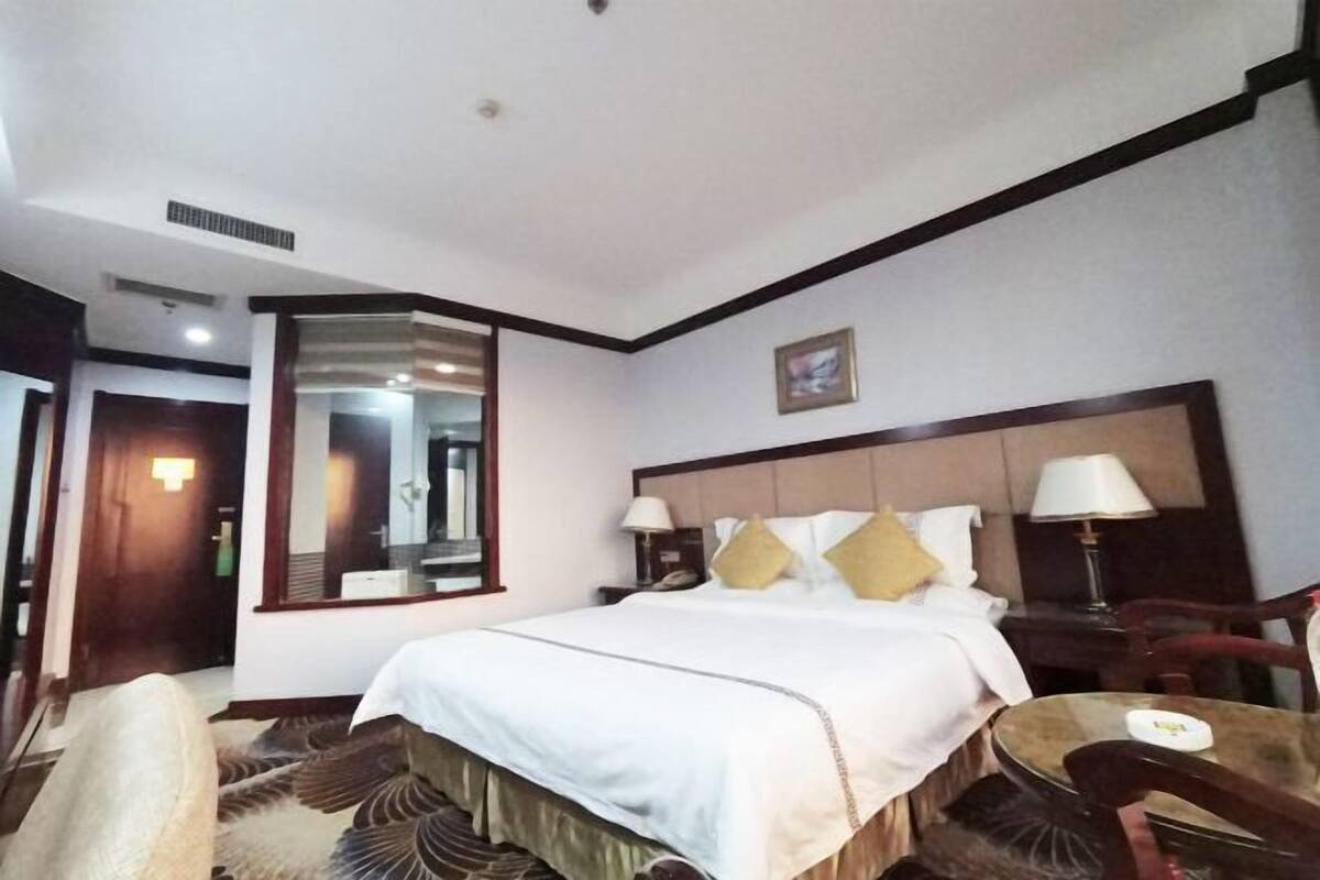 Une chambre d’hôtel avec un grand lit, deux tables de chevet avec des lampes, une table ronde et une chaise.