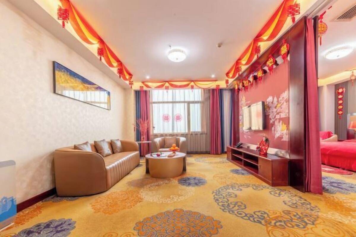 Une chambre d’hôtel avec un canapé, une table basse, une télévision et un lit.