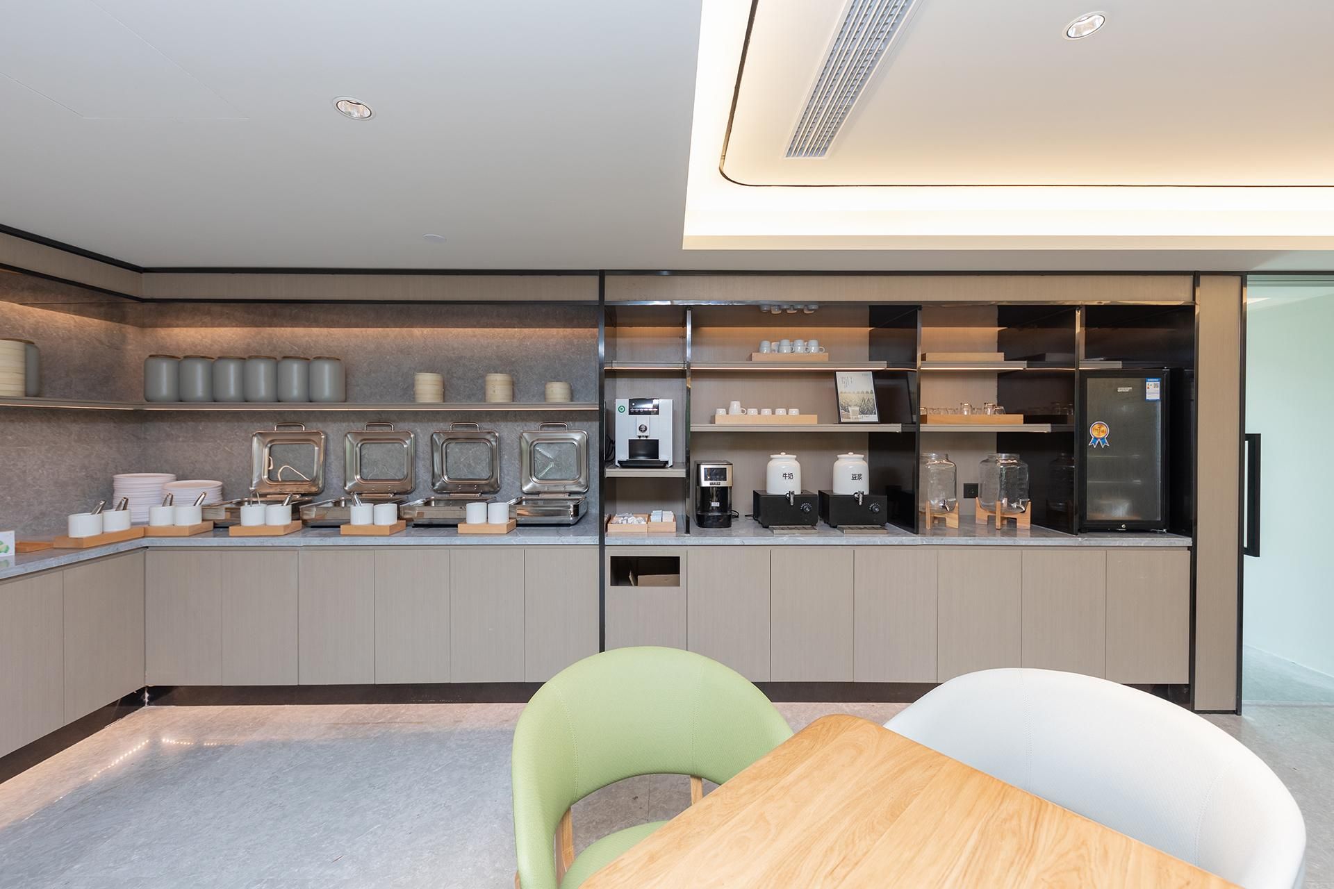 A modern kitchen with a coffee machine, tea station, and a refrigerator.