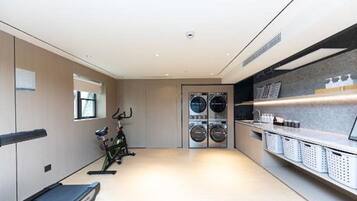 A modern hotel room with a treadmill, a bicycle, and a laundry area.