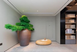 Un interior moderno con una planta grande en maceta, un taburete de madera redondo y un mueble de estanterías empotrado.